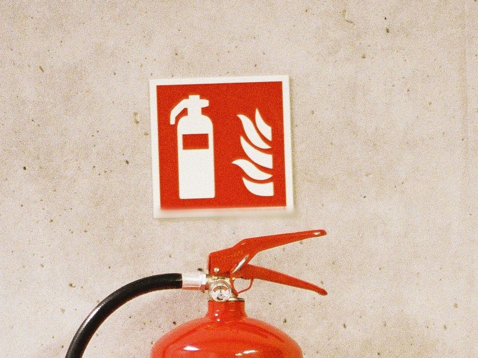 Extincteur sous son pictogramme, sur un mur en béton